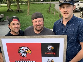 Scott Mace (left), former vice president of the Mitchell Hawks; current Hawks' President Cory Broughton and graphic designer Tom Fanson unveil the team's new logo during the club's annual general meeting July 20 at the Mitchell Lions Park. ANDY BADER/MITCHELL ADVOCATE