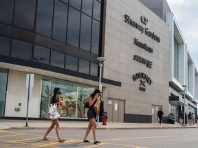 Two women carrying shopping bags cross the street in front of Sherway Gardens during the stage two reopening from coronavirus disease (COVID-19) restrictions in Toronto, Ontario, Canada June 30, 2021.