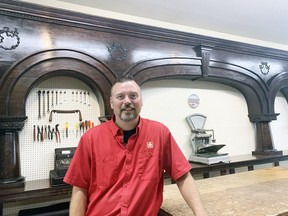 In just a matter of days, what remains of a 150-year-old 20-foot cherry bar from the Hicks House hotel downtown was moved to Faust Home Hardware, and owner Elliott Faust is happy with the move. Faust and a few friends and employees were able to salvage the bar and found a permanent home close to the receiving area of the hardware store. An antique cash register and a scale can be seen behind Faust on the new counter top. ANDY BADER/MITCHELL ADVOCATE