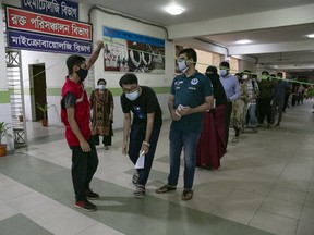 People queue to receive COVID-19 vaccines on July 6 in Dhaka, Bangladesh. Bangladesh enacted a nationwide lockdown on July 1 in an effort to contain a third wave of coronavirus as cases have surged, fuelled by the Delta variant first detected in neighbouring India.