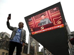 A woman takes a selfie as Chinese President Xi Jinping's speech is broadcasted on a large screen in Beijing during the 100th anniversary of the founding of the Communist Party of China on July 1.