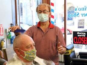 Dino Bartzis of Dino's Barber Shop combs the hair of Randy Conroy on June 12, 2020, after COVID-19 pandemic restrictions were eased in 2020, allowing barbershops to reopen. Bartzis died on Sunday, July 4, 2021.