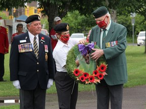 Pembroke Legion President Stan Halliday, left, looks on as executive member Laurette Halliday hands Korean War veteran John Henshaw a wreath to lay in remembrance of fallen comrades during a Canada Day service at the Pembroke waterfront.