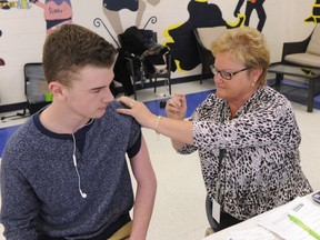 A nurse administers a shot to a high school student. FILE PHOTO