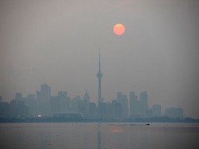 The sun rises through a cover of wildfire smoke above the CN Tower and downtown skyline in Toronto, Ontario, on July 20, 2021. The haze has also drifted over the Sudbury area, but the air quality here has remained good. REUTERS/Carlos Osorio