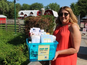 Tracy Pound, executive director of Literacy Lambton, holds a pop-up little free library bin Wednesday at the Children's Animal Farm in Sarnia's Canatara Park. The agency is placing pop-up free libraries to distribute books at parks and beaches around the community.