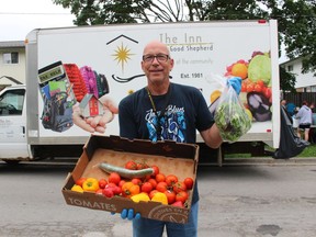 Jef Heynen, mobile market coordinator with the Inn of the Good Shepherd, holds up some of the produce available this week at a stop on Kathleen Avenue in Sarnia. The market makes 14 stops each week during the summer and fall to provide fresh produce to food bank users around Lambton County.