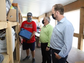 Brandon Brown, left, of the thrift store of Saint Vincent de Paul Society, St Kevin's Conference in Val Caron, Ont., explains his job duties to Nickel Belt MP Marc Serre and Sudbury MP Paul Lefebvre on Wednesday July 14, 2021. The local politicians visited the establishment to announce more than $3.8 million in funding to support youth jobs in both ridings. Brown is one of two new employees at the thrift store that were hired because of the funding. John Lappa/Sudbury Star/Postmedia Network