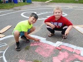 Cameron King, 9, left, and Jeffrey Yaw, 7, help to paint a section of a courtyard mural at Place Hurtubise in Sudbury, Ont. on Wednesday July 28, 2021. John Lappa/Sudbury Star/Postmedia Network