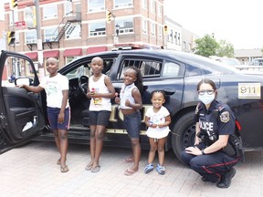 Morgan Tjeriko, from left, with his brother Patrick and their sisters Celine Kuhanga and Adele Hakuria, were drawn by some of the emergency vehicles on display during the Urban Park kickoff on Wednesday. They are seen here with Timmins Police Const. Caroline Rouillard.

RICHA BHOSALE/The Daily Press