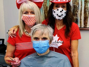 The Canada Day party started early at the Blade Salon in Port Dover on June 30 now that the latest province-wide pandemic lockdown on stylists and beauticians has been lifted. In back, from left, are Blade stylists Tammy Hutchinson and Eddie Alaimo. In the chair is client Joyce Seely. Monte Sonnenberg/Postmedia Network