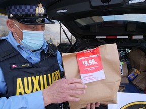 Oxford OPP Auxiliary's Jim Brotz holds a donated bag of food at Metro Tillsonburg during a Cram the Cruiser event to support the Helping Hand Food Bank. (Chris Abbott/Norfolk and Tillsonburg News)