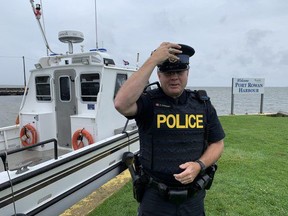 Acting Sgt. Ed Sanchuk held onto his hat Sunday at the Port Rowan marina where a large police presence had prepared to deal with hundreds of partying boaters at the annual party held at Pottahawk Point. Susan Gamble/Postmedia Network