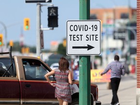 Activity near a sign for a COVID-19 test site in Winnipeg on Friday, July 9, 2021.