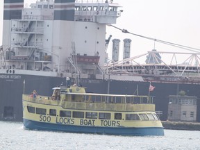 Soo Locks Boat Tours passes by American Integrity entering Soo Locks in Sault Ste. Marie, Mich., on Thursday, Aug. 5, 2021. (BRIAN KELLY/THE SAULT STAR/POSTMEDIA NETWORK)