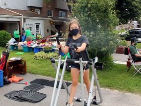 Addison Rioux tries out a piece of exercise equipment offered at the yard sale in support of Camp Caritou, Saturday.
PJ Wilson/The Nugget