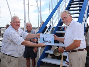 Author John More presents a copy of "Setting the Mark," a history of the Kingston Yacht Club, to KYC commodore Rob Crothers during the book's launch Thursday afternoon. Looking on is contributor and former commodore Ross Cameron.