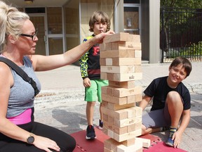 Sarah Wing was seen playing Jenga game with her sons, five-year-old Carsen and eight-year-old Nixen, during the final day of Urban Park activities on Wednesday. RICHA BHOSALE/THE DAILY PRESS