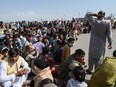 Afghan passengers sit as they wait to leave the Kabul airport in Kabul on August 16, 2021, after a stunningly swift end to Afghanistan's 20-year war, as thousands of people mobbed the city's airport trying to flee the group's feared hardline brand of Islamist rule.