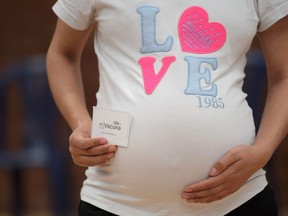 A pregnant woman shows the vaccination card after receving a dose of the Pfizer-BioNTech vaccine against COVID-19 at a vaccination center in Bogota, on July 23, 2021.