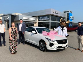 Displaying the Cadillac that's now the prize in a Belleville General Hospital Foundation raffle are, from left, late car dealership owner Peter Smith's son and widow, Matt and Vicki Smith, new dealer principal Cole Allinger, Dr. Max the Moose, and the foundation's Steve Cook.