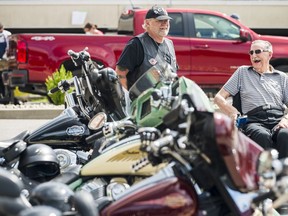 Terry, right, a resident of Quinte Gardens Retirement Residence, laughs alongside a member of the local Quinte Chapter of the Southern Cruisers Riding Club as they view some of the motorcycles on display Sunday in the residence's parking lot in Belleville, Ontario. ALEX FILIPE