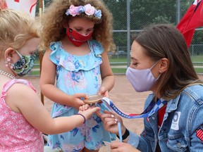 Six-year-old Catherine Dickson and her sister Sophia, 4, of Brantford, get a close up look at Erika Polidori's Olympic medal on Friday, August 13. The girls were among the those who celebrated the Brantford Olympian at a ceremony held at Lions Park. MICHELLE RUBY