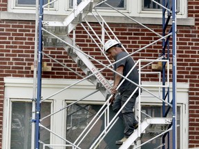 Jorge Rites, of Ottawa-based Simluc Contractors, walks down a scaffold as workers do a roofing job at Brockville Collegiate Institute on Wednesday afternoon. The work is being done ahead of a return to school next month.  (RONALD ZAJAC/The Recorder and Times)