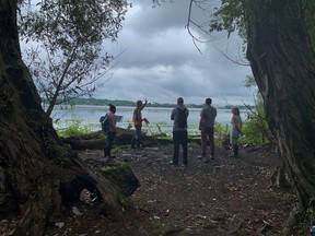 Participants on a tour of the former Davis Tannery property stand along the shoreline of the property in Kingston, Ont., on Aug. 18, 2021.
