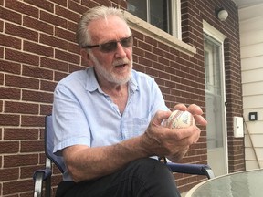 Doug McIlroy, 78, illustrates the grip he used on his celebrated fastball, the "fastest pitch on this side of the limestone shelf."