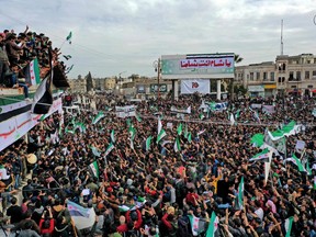 An aerial picture shows Syrians waving the national flag during a gathering in the rebel-held city of Idlib on March 15, 2021, as they mark 10 years since the nationwide anti-government protests that sparked the country's devastating civil war. In the jihadist-dominated stronghold's main city, crowds marched down the street, some waving the opposition's three-star flag or holding up images of those killed during the conflict. Syria's war has killed more than 388,000 people and displaced millions of Syrians inside the country and abroad.