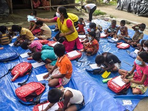 In this photo, taken on July 23, 2021, children of a low-income neighbourhood attend a class at an open-air school set up by the non-profit Unique Foundation at Porajhar village on the outskirts of Siliguri. In India, where schools have been shut for over a year, one of the longest COVID-19 shutdowns in the world, the fear is that many poor children won't return to education even when schools eventually reopen, creating a "lost generation" of unqualified young people.