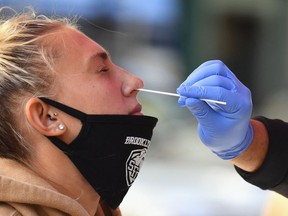 In this file photo a healthcare worker takes a nasal swab sample from a student to test for COVID-19.