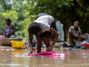A girl washes clothes in a river in the Camp Perrin neighborhood in, Les Cayes, Haiti August 22, 2021. REUTERS/Ricardo Arduengo