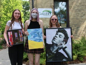 Recipients of this year's Gallery in the Grove scholarships hold examples of their work outside the gallery in Bright's Grove. From left, Carly Chartrand, Ainsley Wrobel and Mariah Dennis. Absent from the photo is scholarship winner Clay LeBlanc.