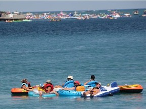 Floaters from the Canadian side in the 2019 Port Huron Float Down make their way down river shortly before 1 p.m., as U.S. floaters in the distance get ready to cast off from the lighthouse in Port Huron. The annual unsanctioned event is scheduled for Sunday. (Observer file photo)