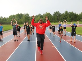 Olympic gold medallist Robert Esmie leads a group of athletes in a warm-up at the track at Laurentian University in Sudbury, Ont. on Tuesday August 3, 2021. An informal celebration was held to honour Esmie at the track. John Lappa/Sudbury Star/Postmedia Network