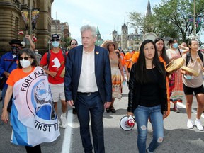 Hundreds joined MPs Charlie Angus, centre, Mumilaaq Qaqqaq and Indigenous elders for a march from Parliament Hill Saturday to demand an independent investigation into the mounting number of unmarked graves found at former residential school sites. 

JULIE OLIVER/POSTMEDIA NETWORK