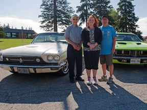 Stratford car enthusiasts LeVern Gould (left) and Jon Carter flank Spruce Lodge activity co-ordinator Kim Luckhardt alongside a 1966 Wimbledon white Thunderbird and a 1972 sublime green Plymouth Barracuda. Both cars will be part of Spruce Lodge’s seventh annual car event Thursday. (Chris Montanini/Stratford Beacon Herald)