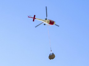 A helicopter carries a nearly 1-ton rock containing a newly found dinosaur skull of our the Redwillow River valley.