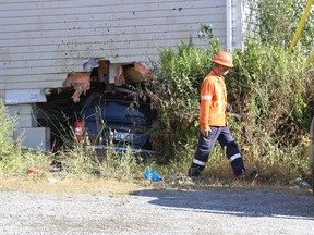 A Utilities Kingston employee works to shut off gas to a house on Montreal Street after a Jeep was driven into the side of it early Thursday morning.