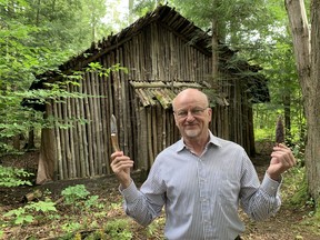 John Benson is raising funds for an in-depth study of the first people to occupy south-central Ontario following the end of the last Ice Age 13,000 years ago. Here, Benson displays flint tools in front of the replica aboriginal longhouse he built on his property north of Marburg. – Monte Sonnenberg