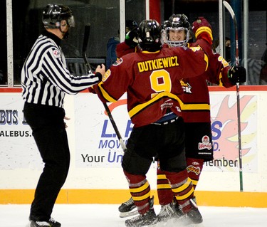 Timmins Rock forward Christopher Engelbert is all smiles as he celebrates his game-winner overtime goal with teammate Cameron Dutkiewicz as linesman Matthew Vanderweerden looks on during Sunday’s NOJHL contest at the McIntyre Arena. With the 2-1 victory the Rock improve to 2-0-0-0 on the season. THOMAS PERRY/THE DAILY PRESS