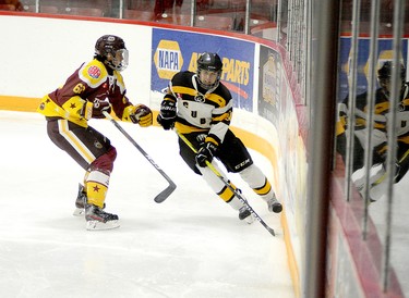 Braedon Dorrell, of the Cubs, gets rid of the puck just before taking a hit from Timmins Majors forward Nathan Dutkiewicz behind the New Liskeard net during the second period of Saturday’s Great North U18 League exhibition contest at the McIntyre Arena. The two sides skated to a 1-1 tie. THOMAS PERRY/THE DAILY PRESS