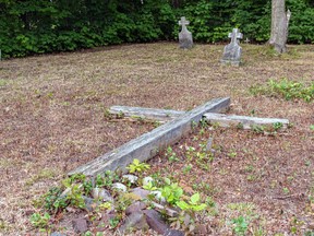 Volunteers Gayle Russell and Karen McLean have kept the grass trimmed at St. Aloysius Cemetery, but the large cross at the centre now lies flat on the ground. The tiny wooden cross in the background is one that the two placed there nine years ago, to mark a spot they believe  contains a grave.