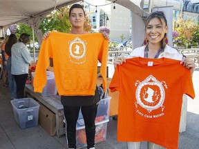 Evan Cabral and Shania Simon were two of many people selling orange shirts at Covent Garden Market as part of an Atlohsa Family Healing Services campaign. Said campaign co-chair Heather Cabral: "It's about bringing together Indigenous and non-Indigenous people for a common cause, which is love and unity." More than 10,000 shirts have been sold since July. Profits from the sales fund the Atlohsa's Minow Bimaadizwin youth program. (Derek Ruttan/Postmedia)