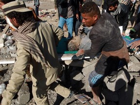 Yemeni men carry a man after pulling him from under the rubble of a building destroyed by Saudi air strikes in Yemen.