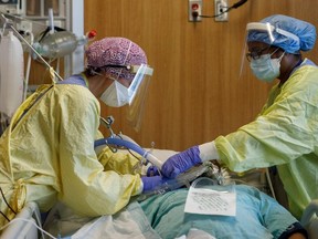 Redeployed nurses Angela Bedard, left, and Andrea Blake tend to a patient suffering from COVID-19 at Humber River Hospital's Intensive Care Unit in Toronto on April 28, 2021.