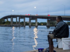 Rey Naoe fishes Saturday evening in front of the Belleville Bay Bridge on the Bay of Quinte in Belleville, Ontario. ALEX FILIPE