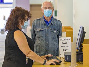 Sandra Piet, information assistant at the Brantford Public Library's main branch in downtown Brantford helps Paul Olsen of Tillsonburg print his proof of vaccination on Wednesday September 22, 2021 in Brantford, Ontario. Proof of vaccination requirements went into effect today for people to enter restaurants, gyms and other non-essential places across the province. The library is offering the service of charge. Brian Thompson/Brantford Expositor/Postmedia Network